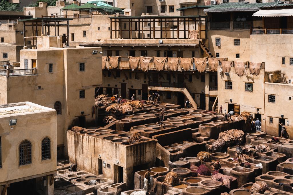 Image of a leather tanning complex. A row of hanging leather sheets are drying in the sun from a balcony.